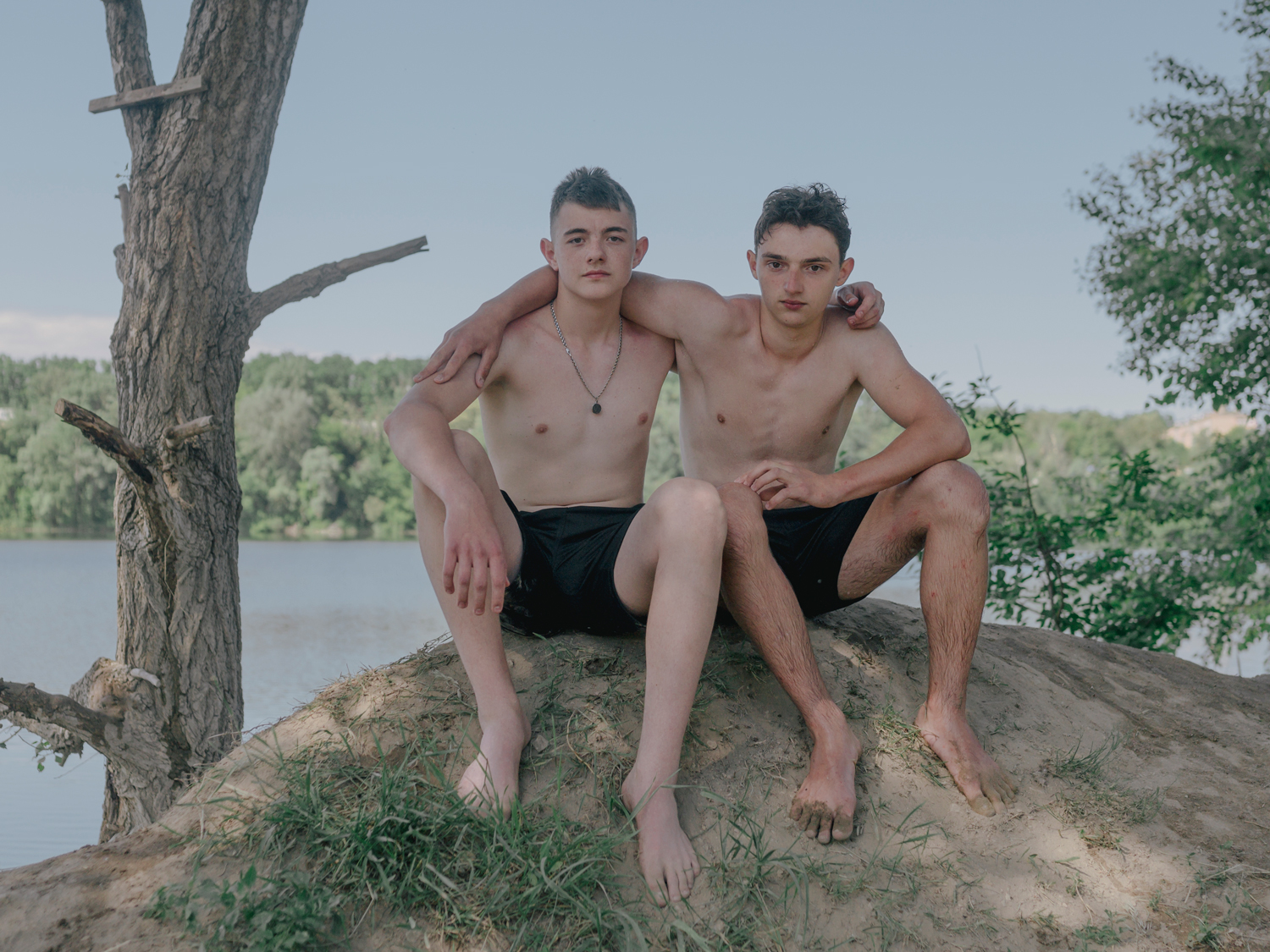 Grisha (left) and Borys (right), two best friends, pose for a portrait nearby Irpin. Grisha lives in Irpin, Borys is from Bucha. Grisha just got out of Irpin half an hour before the russians took the street where he lives with his family, this day marks the first day, they go for a swim at the lake. Kyiv Oblast, 06.06.2022